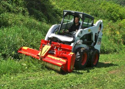 SMWA Skid Steer in action on a bobcat, clearing a slope
